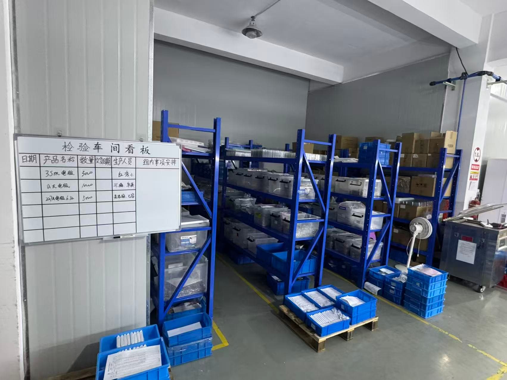 Inspection workshop area with storage racks, parts bins and a status board